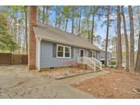 Charming blue home with a brick chimney and a landscaped front yard surrounded by mature trees at 1010 Flanders St, Garner, NC 27529