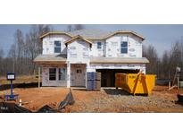 New construction home with Tyvek wrap, showing framing and preparation for exterior finishes with construction debris in front at 1135 Winding Spring Dr, Mebane, NC 27302