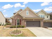 Charming brick home featuring a two-car garage, manicured lawn, and freshly planted tulip garden at 1524 Catch Fly Ln, Durham, NC 27713