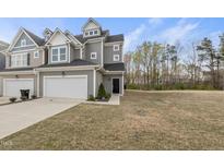 Charming gray townhome boasts an attached garage, manicured lawn, and inviting entryway, blending comfort and style at 248 Shingle Oak Rd, Wake Forest, NC 27587