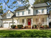 Charming two-story home featuring a welcoming front porch, landscaped yard, and bright red front door at 317 Flatrock Ln, Holly Springs, NC 27540