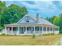 Charming home featuring a full wraparound porch, a stone chimney, and beautiful mature landscaping at 468 Loftis Loop Rd, Roxboro, NC 27574