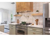 Gourmet kitchen featuring stainless steel appliances, custom backsplash, and a modern range at 1008 North St, Durham, NC 27701