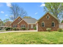 Charming brick home featuring arched windows and a well-manicured lawn on a sunny day at 1517 Woodland Ave, Burlington, NC 27215