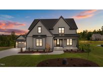 Stunning two-story home with gray siding, black trim, and a well-manicured lawn at sunset at 20 Serenity Woods Trl, Franklinton, NC 27525