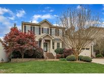Charming two-story home featuring a manicured lawn and inviting front porch at 317 Briarfield Dr, Apex, NC 27502