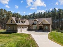 Charming home with a well-manicured lawn, three-car garage, stone accents, and mature trees at 3220 Brassfield Rd, Creedmoor, NC 27522