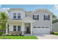 Charming two-story home featuring a covered porch, two-car garage, and a beautifully landscaped front yard at 3849 Rosebush Dr, Zebulon, NC 27597