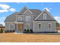 Beautiful two-story home with a grey exterior, manicured lawn, and inviting front porch showcasing curb appeal at 45 Melody Dr, Youngsville, NC 27596