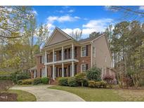 Charming two-story brick home with a large front porch and manicured landscaping at 5521 Erinvale Ct, Holly Springs, NC 27540