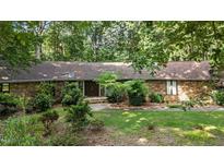 Charming stone home featuring a unique roofline and lush landscaping at 8805 Leesville Rd, Raleigh, NC 27613