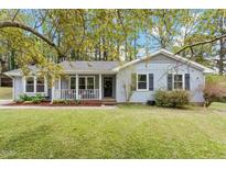 Charming single-story home with a covered front porch and well-maintained landscaping in a serene, wooded setting at 1107 Edgebrook Dr, Garner, NC 27529