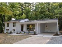 A charming single-Gathering home featuring a white exterior, a covered carport, and a well-manicured lawn with mature trees at 245 Marilyn Cir, Cary, NC 27513