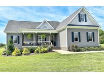 Charming gray home featuring a welcoming front porch, landscaped yard, and stylish architectural details at 2540 Levi Ln, Bahama, NC 27503