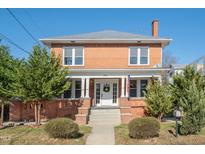 Charming brick home with a welcoming front porch, surrounded by mature trees and lush landscaping at 301 E Umstead St, Durham, NC 27707