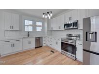 Bright kitchen features white cabinets, stainless steel appliances, white subway tile backsplash and hardwood floors at 301 E Umstead St, Durham, NC 27707