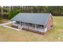 Charming single-story home featuring a welcoming porch, neutral siding and brick accents, set in a wooded area at 3026 Shoeheel Rd, Kenly, NC 27542