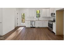 Bright kitchen featuring white cabinets, stainless steel appliances, and access to an outdoor deck at 306 Cecil St, Durham, NC 27707