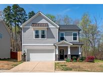 Charming two-story home with a gray shingle facade, attached garage, and well-maintained landscaping at 433 Mockingbird Ln, Mebane, NC 27302
