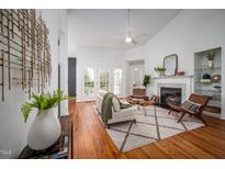 Bright living room boasts a fireplace, hardwood floors, ceiling fan, and access to the outdoor deck through French doors at 6 Preakness Dr, Durham, NC 27713