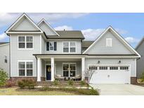 Charming two-story home with a well-manicured lawn, a covered porch and a two car garage at 705 Marshall Farm St, Wake Forest, NC 27587