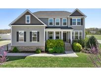 Beautiful two-story home featuring a well-manicured lawn, lush landscaping, and a welcoming front porch at 834 November Ln, Willow Springs, NC 27592
