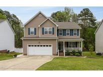 Charming two-story home with a well-manicured lawn, a two-car garage, and a welcoming front porch at 136 Ashlyn Ridge Dr, Garner, NC 27529