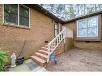 Brick home entrance with stairs, white railing, security system, and tidy landscaping at 200 W Woodcroft Pkwy # 37A, Durham, NC 27713