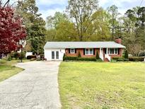 Charming brick home features a well-manicured lawn, a basketball hoop, and a long driveway at 3711 Halford Dr, Raleigh, NC 27604