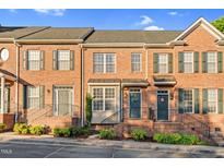 Brick townhome with well-maintained landscaping, multiple windows, and stylish doors under a sunny blue sky at 4 Scottish Ln, Durham, NC 27707
