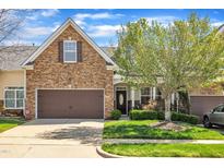 Charming townhome with stone accents, a brown garage door, manicured lawn and inviting curb appeal at 5033 Homeplace Dr, Apex, NC 27539