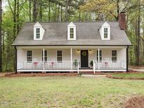 Charming home with inviting front porch, rocking chairs, and well-maintained yard in a wooded setting at 5209 Rivington Rd, Fuquay Varina, NC 27526