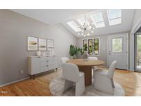 Bright dining room features skylights, modern chandelier, wood floors, and neutral decor for elegant, comfortable dining at 58 Stoneridge Rd, Durham, NC 27705