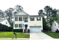 Charming two-story home with white columns, green lawn, and attached two-car garage at 6705 Somerknoll Dr, Durham, NC 27713