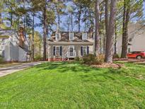 Charming home featuring black shutters, dormer windows, fresh green lawn, and beautiful landscaping at 7117 Sandringham Dr, Raleigh, NC 27613