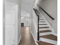 Inviting entryway features hardwood floors and a staircase with black handrail leading to upper level at 8700 Leeds Forest Ln, Raleigh, NC 27615