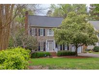 Charming two-story home features a brick chimney, a well-maintained lawn, and mature trees at 1159 Belfair Way, Chapel Hill, NC 27517