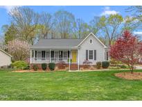 Charming single story home with a well-maintained lawn, inviting porch, and attractive landscaping at 124 Holly Ridge Ln, Mebane, NC 27302