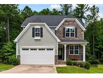 Charming home featuring stone accents, gray shingles, a white garage door and a cozy front porch at 128 School Side Dr, Spring Lake, NC 28390