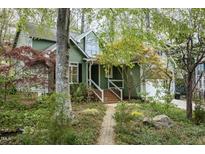 Charming green home with brick pathway, lush landscaping, and inviting front porch at 1550 Pathway Dr, Carrboro, NC 27510