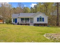 Charming white house with blue accents, a welcoming front porch, and a lush green lawn at 163 Ridge Way Ln, Clayton, NC 27520