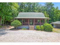 Charming log cabin featuring a covered porch, complemented by mature trees and a gravel driveway at 207 High House Rd, Cary, NC 27513