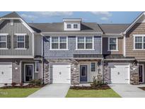 Charming townhome showcasing stone accents, individual garages, and appealing curb appeal with manicured landscaping at 2112 Willow Gln Dr, Graham, NC 27253