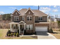 Charming two-story home boasts a stone and brick facade, attached two car garage, and a well-manicured front yard at 2713 Tunstall Grove Dr, Apex, NC 27523