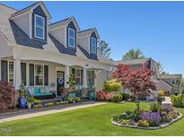 Charming two-story home with dormer windows, lush landscaping, and inviting front porch at 49 Everwood Dr, Four Oaks, NC 27524