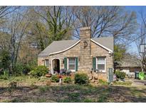 Charming stone cottage with green shutters and a unique architectural design, surrounded by lush greenery at 4914 Western Blvd, Raleigh, NC 27606