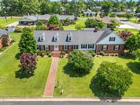 Charming brick home with lush landscaping, dormer windows and a brick walkway on a large lot at 504 W Brocklyn St, Benson, NC 27504