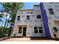 Unfinished exterior of a new construction home, wrapped in Tyvek HomeWrap, with windows installed and the framing exposed at 6960 Doddridge Ln # 15, Cary, NC 27519