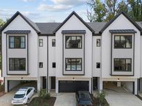 Modern townhome exterior featuring black trim, white siding, a garage, and driveway at 810 Maple Berry Ln # 105, Raleigh, NC 27607