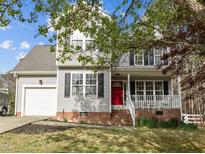 Charming two-story home featuring gray siding, black shutters, a red front door, and a welcoming front porch at 125 Camden Dr, Youngsville, NC 27596
